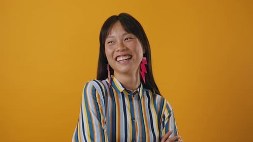 Smiling Young Woman Laughs on Yellow Background