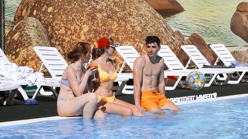 Two girls flirting with young man by the swimming pool
