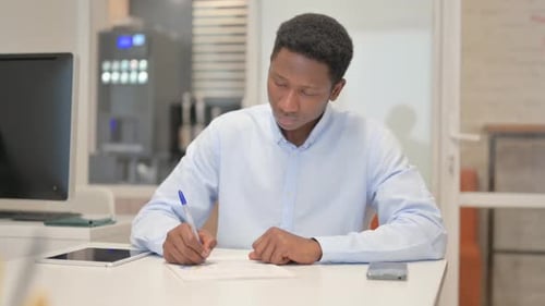 African Businessman Working on Documents in Office