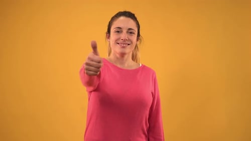 Smiling Woman Gives Thumbs Up on Yellow Background