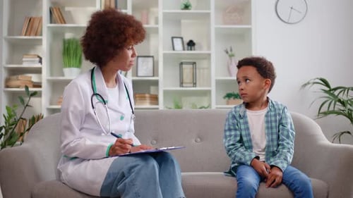 Caring Female Baby Doctor Having Appointment with Little Boy in Medical Office