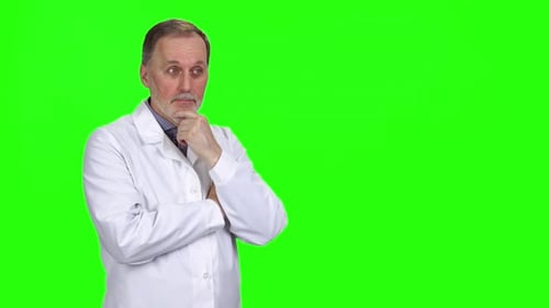Happy Aged Male Doctor in White Coat Thinking and Pointing at Copy Space