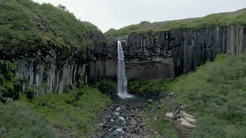 Svartifoss Waterfall At Summer Within The Vatnajokull National Park In Iceland. - aerial pullback