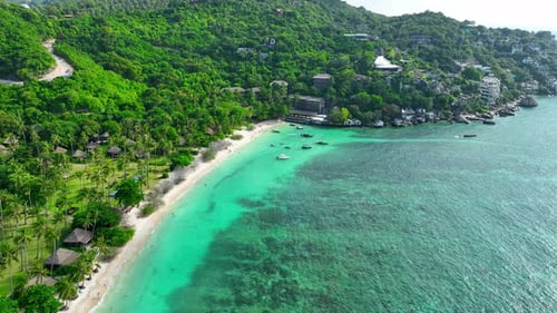 Sandy beach shore with beautiful resort surrounded by clear sea water.