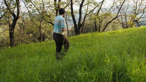 Young Farmer Walking On The Green Meadow In The Countryside