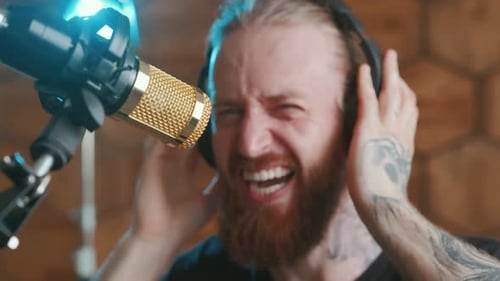 Young Caucasian Man Presses Headphones and Sings Loudly Recording New Rock Album