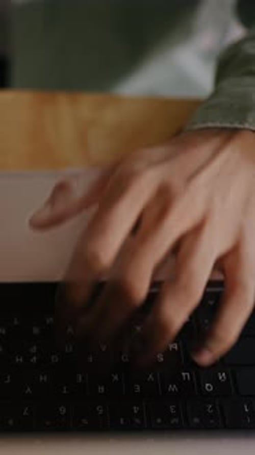 Young Man Types on Laptop Trackpad Indoors