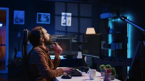 IT-Administrator denkt nach und trinkt Kaffee, während er früh am Morgen am PC arbeitet