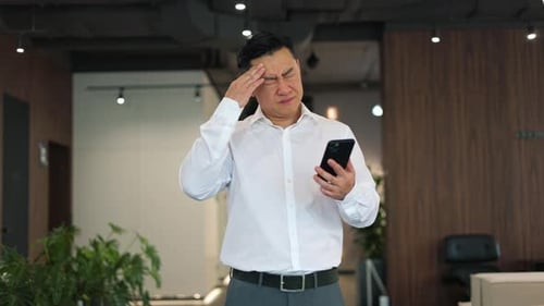 Adult with Headache Looking at Phone in Office