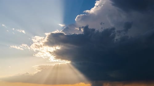 Untergehende Sonnenstrahlen scheinen durch dunkle Gewitterwolken, Wetter in Bewegung