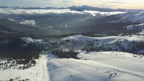 Snowy mountain landscape over looking a vast valley at sunset in winter