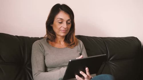 Woman Using Tablet Device on Comfortable Couch