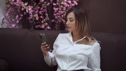Young Woman Using Phone While Sitting on Couch
