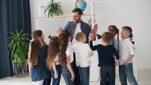 Giving high five to the man. Successful lesson. Group of children students in class at school
