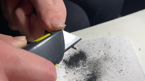 Girl sharpening a mechanical lead pencil, with a blade, close up.