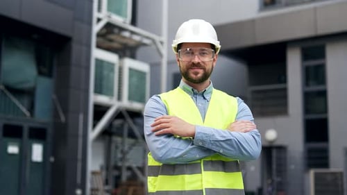 Portrait of smiling professional engineer wearing safety helmet, protective glasses and vest stand