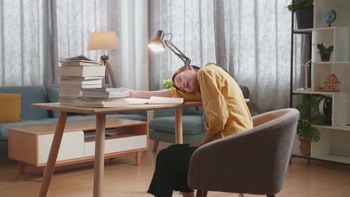 Side View Of Young Asian Female Studying At Home Sleeping While Reading Books On The Table