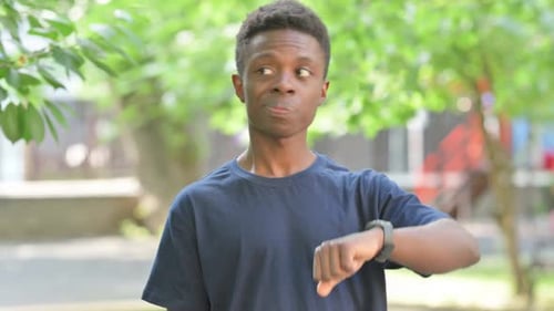 Young Man Checking Watch in Urban Park