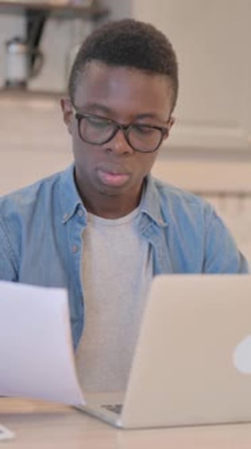 Young Adult Man Working on Laptop with Documents