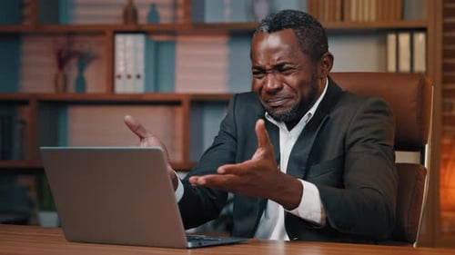 Worried man looking at laptop in office