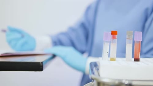 Close-up of an Asian female doctor writing a list of blood test results.