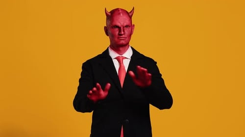 Empresario disfrazado de cuernos de diablo haciendo gestos sobre fondo amarillo