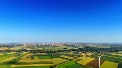 Vast beautiful fields with wind farms. Wind turbines rotate producing green energy. Aerial view.