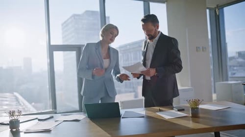 Two Colleagues Looking Documents Discussing Budget in Modern Office Closeup