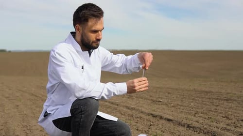 Laboratory Worker Holding Professional Glassware and Testing Black Soil After Harvest in the Field