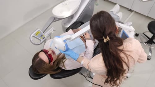 Dentist Providing Professional Teeth Whitening Using Advanced Equipment in Modern Dental Office