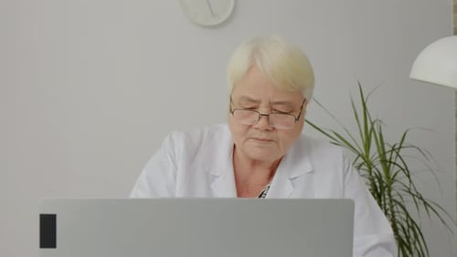 Mature Woman Doctor Working at Computer in Office