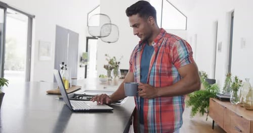 Young Man Works on Laptop at Home with Coffee