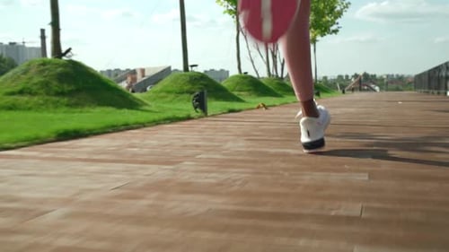 Young african woman runner jogging in city park close up from behind in slow motion