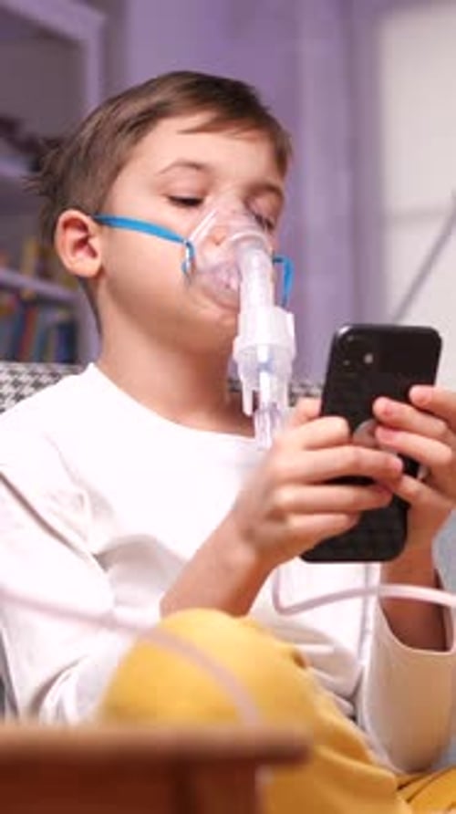 Child Using Nebulizer and Cell Phone