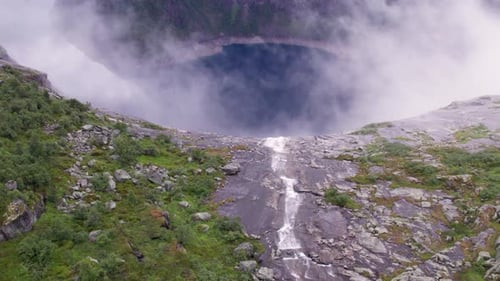 aerial view of norwegian fjords and waterfall through clouds