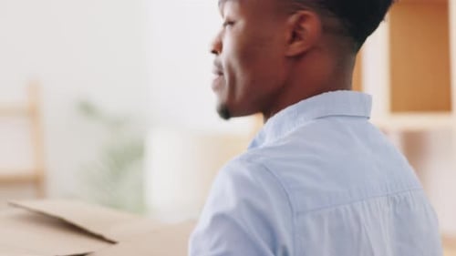 Black man and woman moving boxes in new house living room, real estate property