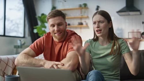 Cheerful Couple Video Calling on Laptop from Sofa