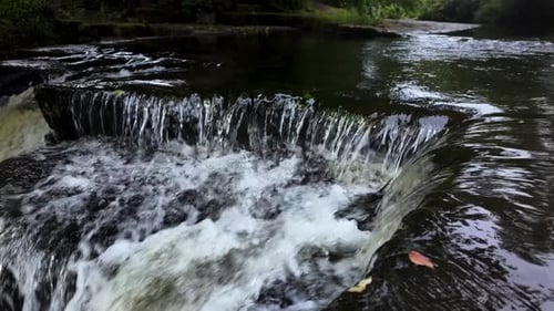 River water flowing over rocks, creating small waterfalls. close up, slow motion