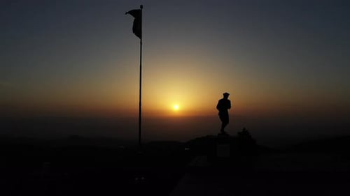 Statue Silhouette with Flag at Sunset