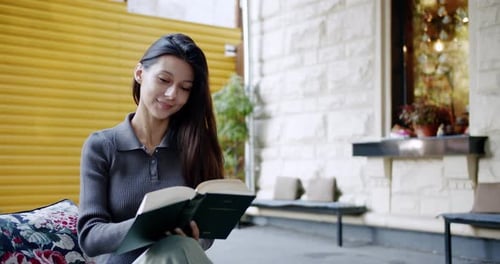 Young Brunette Reading Book on Street
