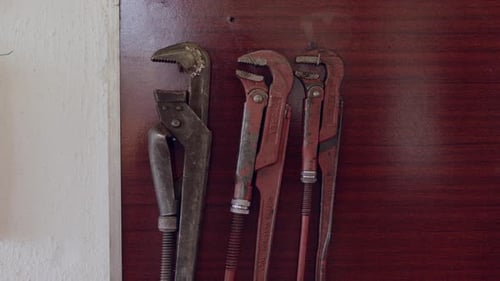 A Variety of Aged Wrenches are Suspended From a Wooden Surface Within a Workshop