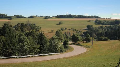 Car driving through green hills and trees on narrow asphalt road. Transportation concept. Road trip