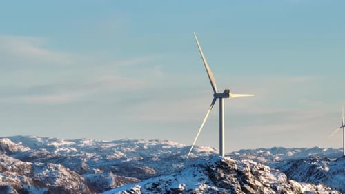 Cinematic Drone Shot of Windmills and Spinning Blades on Top of Mountain Range on Sunny Winter Day