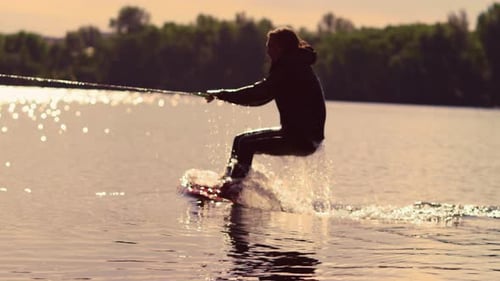 Man wakeboarding on a lake at sunset