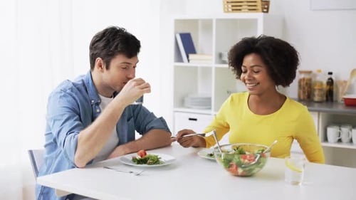 Couple enjoys healthy salad together at bright kitchen table
