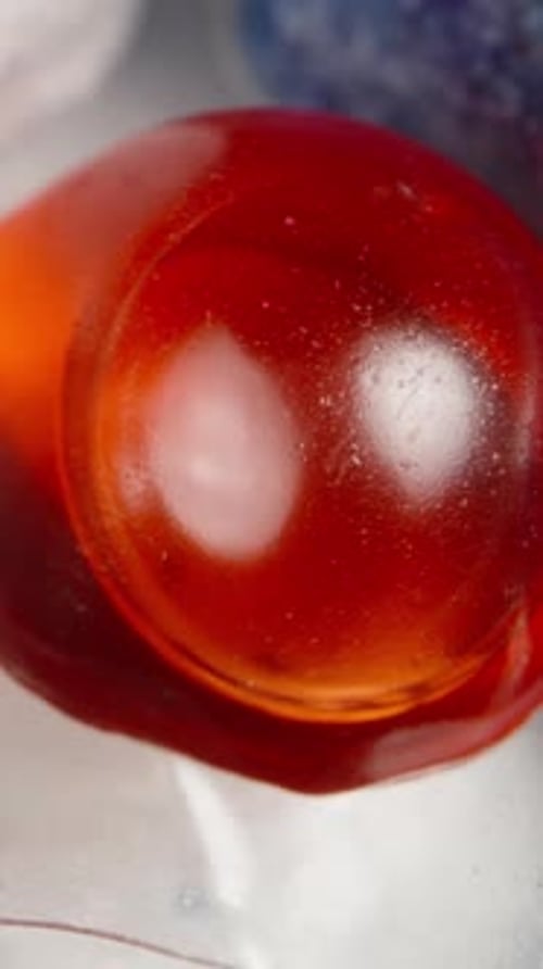 Vertical video. Soluble packets, dishwasher capsules, macro zoom from a top view. White-blue powder