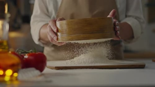 Hands Sifting Flour onto Cutting Board in Kitchen