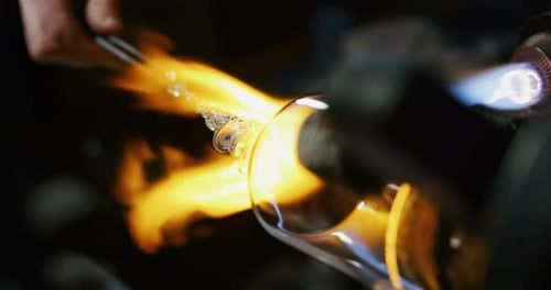 Zeitlupenmakro eines Glasbläsers, der mit Flammen auf einem handgefertigten Kunststück aus Glas von preciou arbeitet