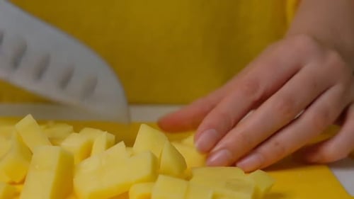 Person Cutting Potatoes into Cubes on Cutting Board