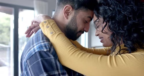 Young Couple Embracing with Foreheads Touching Indoors